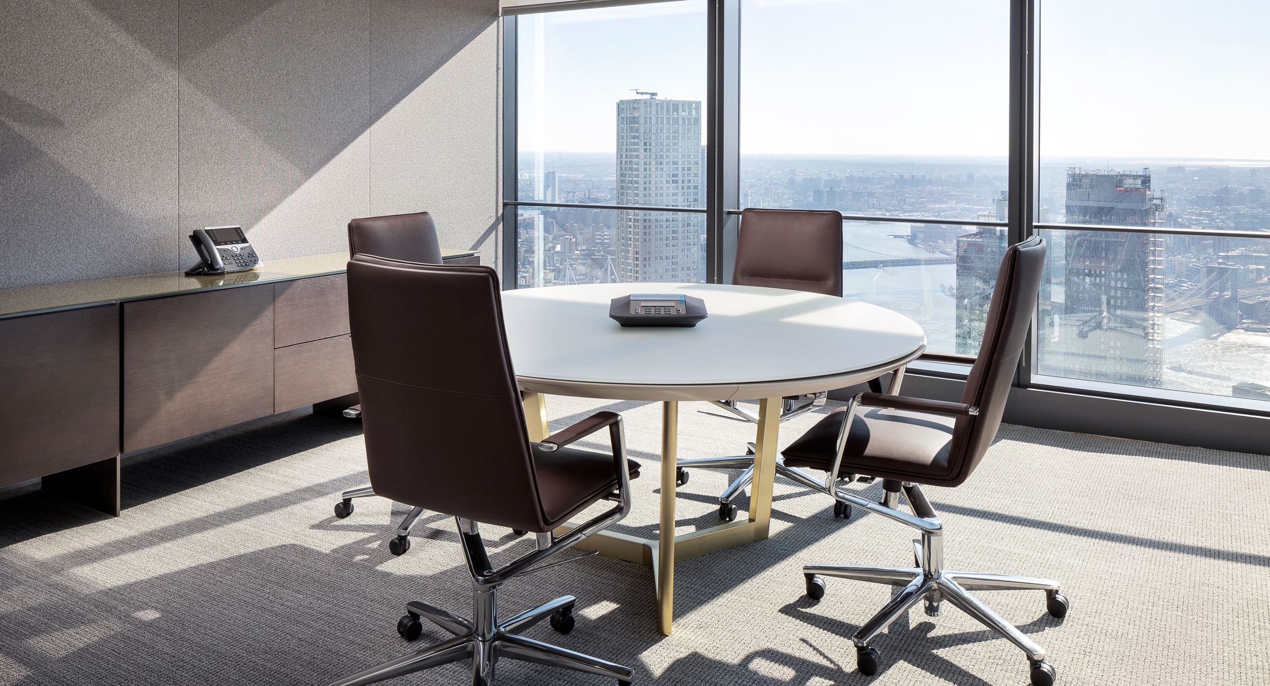 A 60-inch diameter HALO conference table features an etched glass surface with patented HALO soft edge and Brushed Brass base.